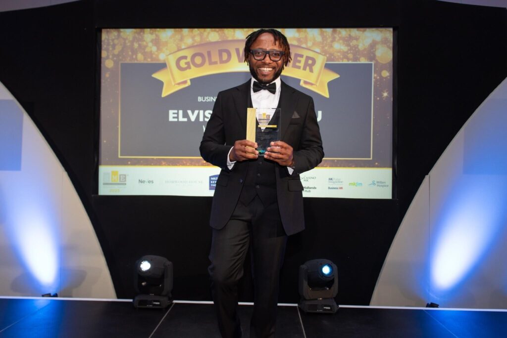 Elvis Idegbekwu, Managing Director of Rosewin Cleaning, holding his Gold Winner trophy for Businessperson of the Year on stage at the 2026 SME MK and Buckinghamshire Business Awards.